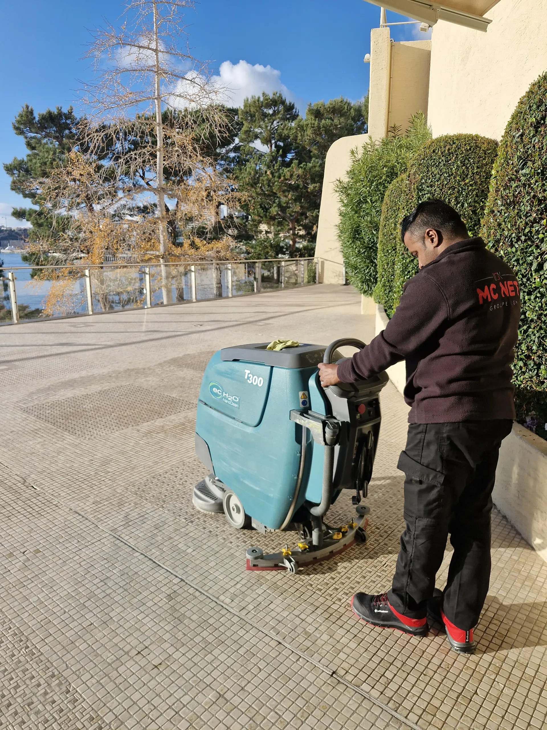 MC NET Cleaning operative with floor scrubber on a seaside terrace